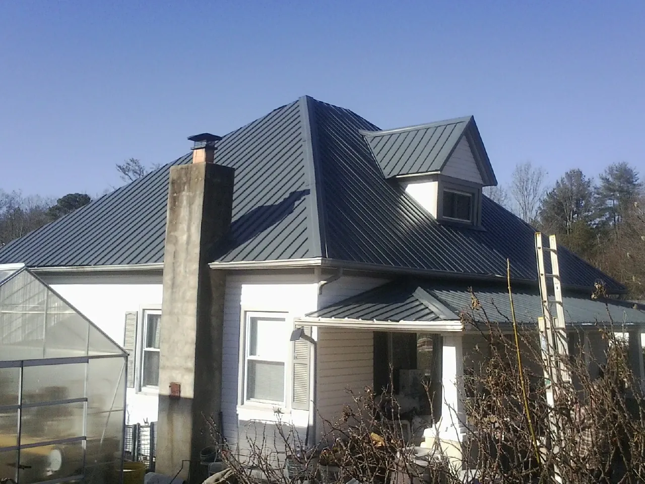 Dark blue standing seam metal roof on a white farmhouse with dormer — Slate & Tile Roof Repair by Roofing Brothers in Strawberry Plains