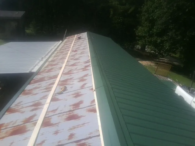 Old rusted panels beside newly installed green metal roofing — Wind Damage Roof Repair by Roofing Brothers in Strawberry Plains