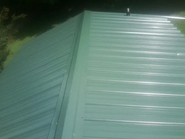 New green metal panels meeting at the ridge of a roof — Flat Roof Repair work by our crew in Strawberry Plains