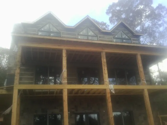 Dormers and porch framing on a large log home under construction — Roof Coating work by our crew in Strawberry Plains