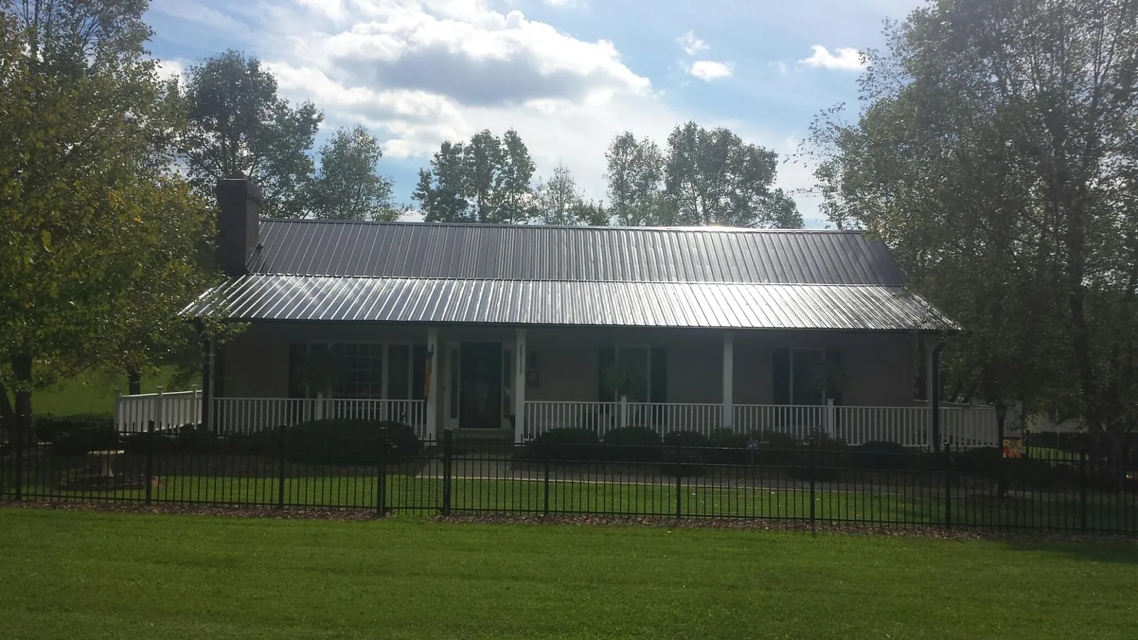 Gray metal roof on a brick ranch with a full width front porch — Gutter Guard Installation work by our crew in Strawberry Plains