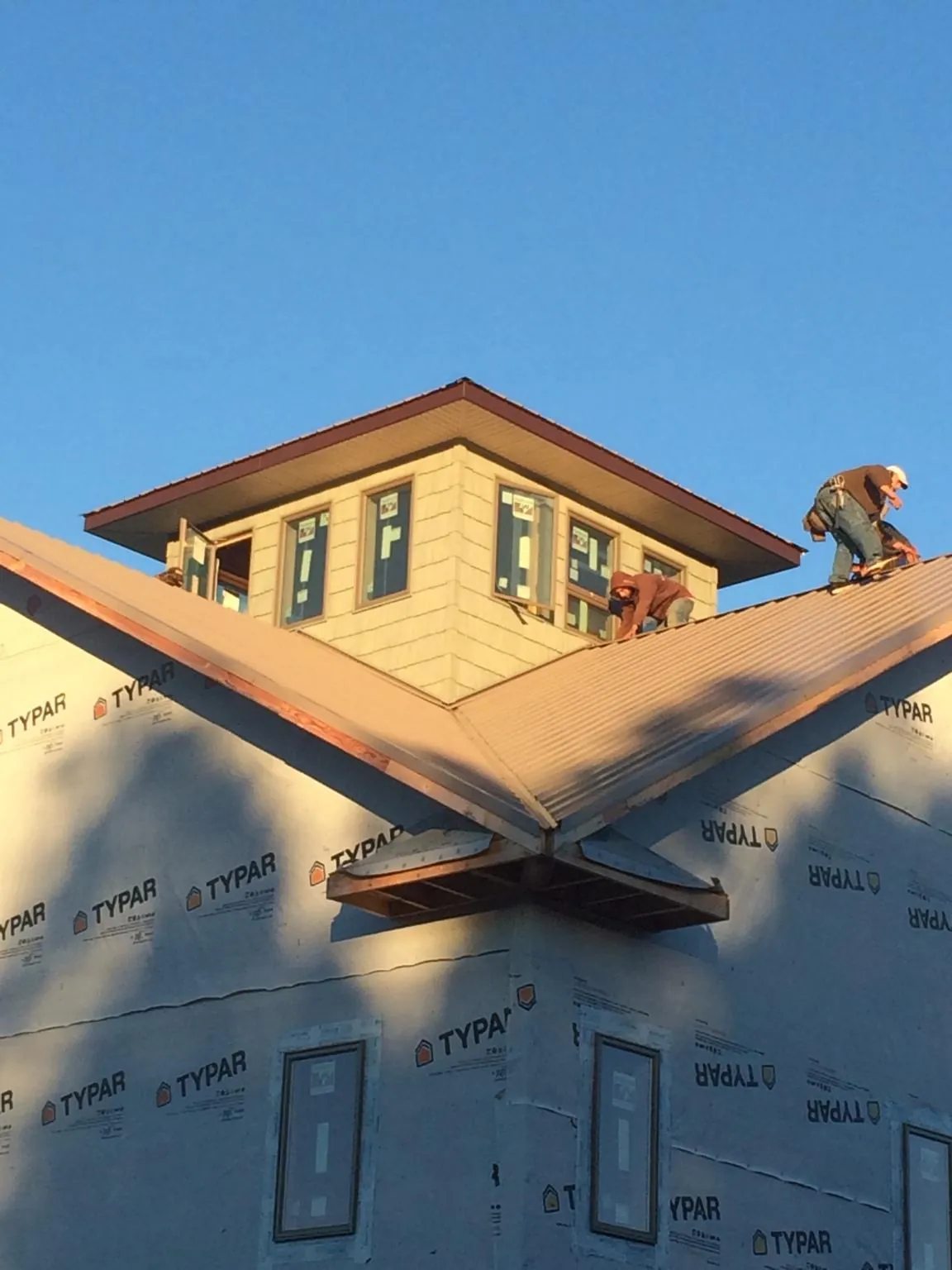 Roofers working around a rooftop cupola on a new metal roof at sunset — Roof Waterproofing in Strawberry Plains by Roofing Brothers